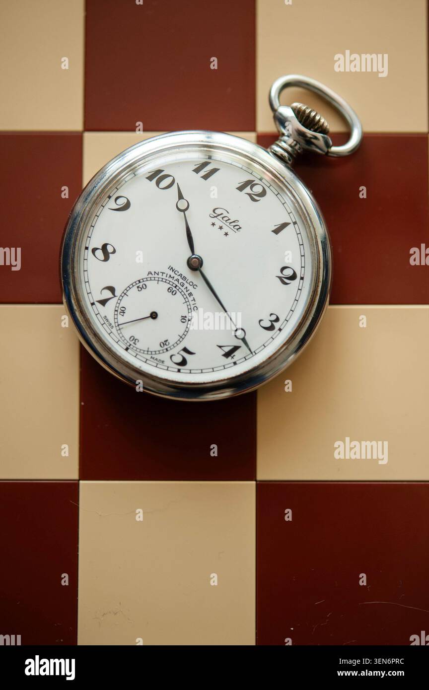 Montre de poche vintage sur un échiquier rouge et crème, nature morte symbolique sur le temps, la stratégie et la prise de décision Banque D'Images