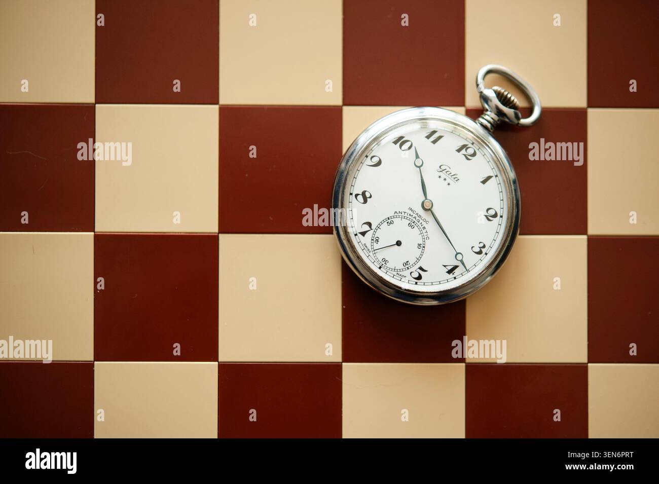 Montre de poche vintage sur un échiquier rouge et crème, nature morte symbolique sur le temps, la stratégie et la prise de décision Banque D'Images