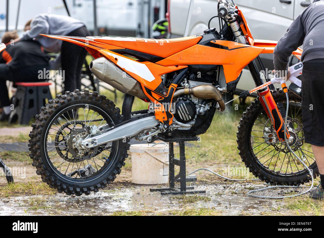 Le mécanicien de l'équipe lave les paddock boueux des motos enduro exigeant une course tout-terrain. Entretien nettoyage préparation technique support sport automobile Banque D'Images