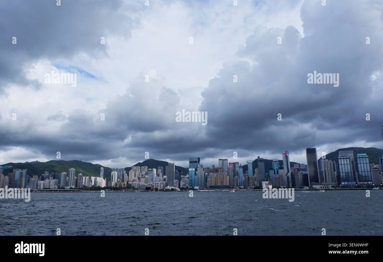 HONG KONG - 18 JUILLET 2023 : un large panorama de nuages sombres et dramatiques de la mousson roulant sur les gratte-ciel de l'île de Hong Kong. Banque D'Images