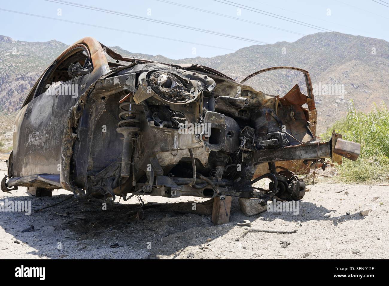 Les restes rouillés d'une épave de voiture brûlée dans le désert du Colorado dans la vallée de Coachella, en Californie, symbolisent la culture américaine des déchets. Banque D'Images