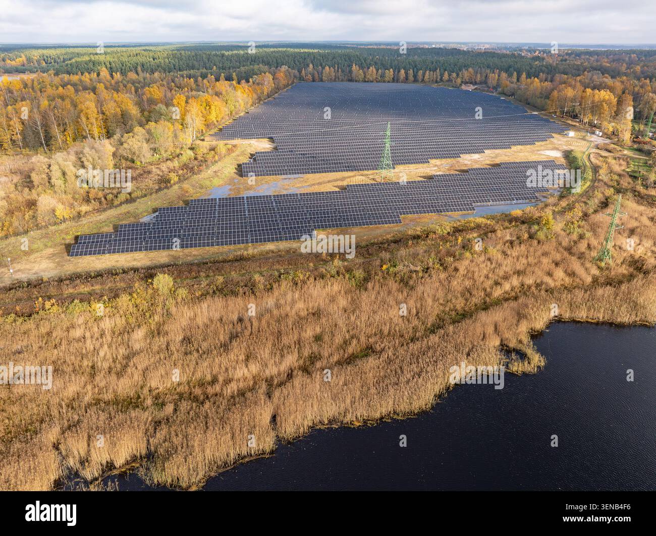 Parc solaire de Jaunciems près de Riga, Lettonie, grande centrale photovoltaïque entourée d'une forêt d'automne, vue aérienne par drone Banque D'Images
