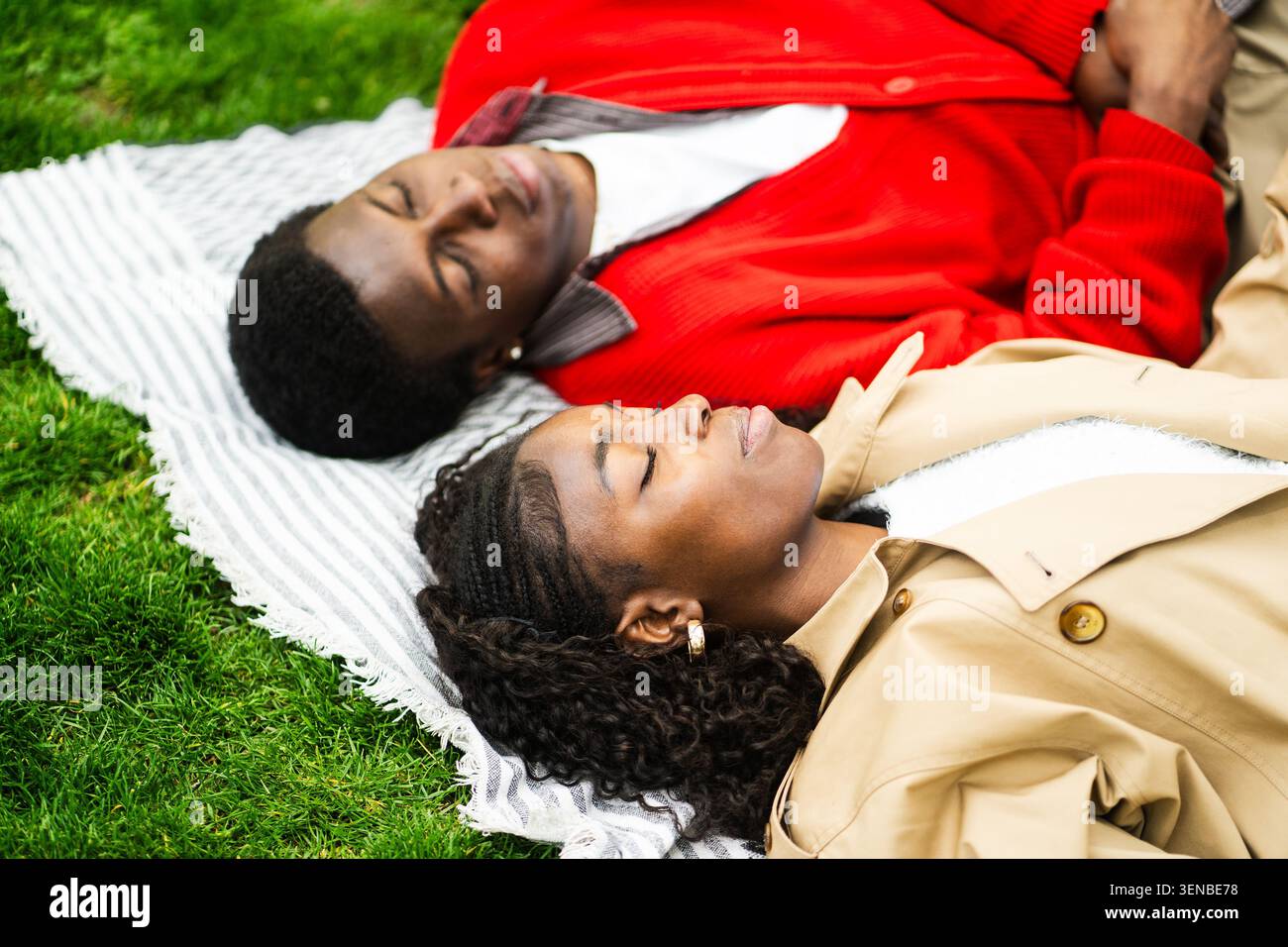 Homme et femme afro-américains insouciants prenant le temps de se reposer à l'extérieur en profitant de la nature dans le parc. Banque D'Images