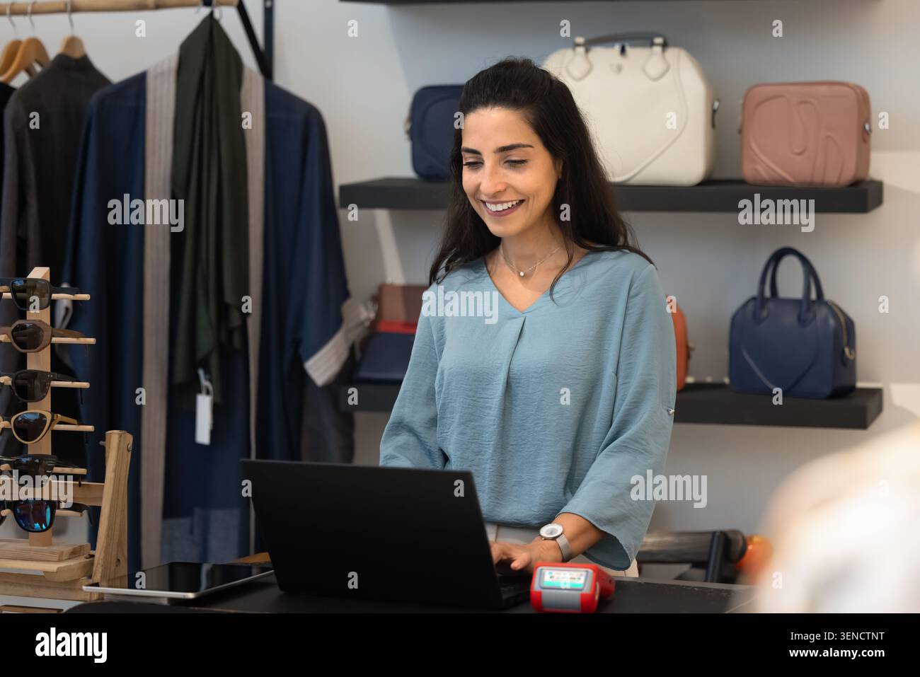 Assistant souriant travaillant sur ordinateur portable à la caisse de la boutique Banque D'Images