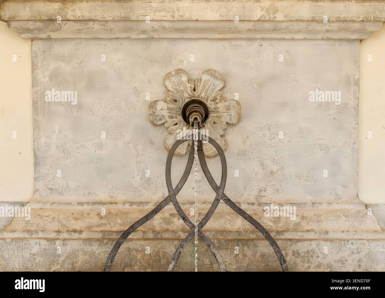 Fontaine murale en pierre historique avec bec décoratif et support en fer forgé Banque D'Images