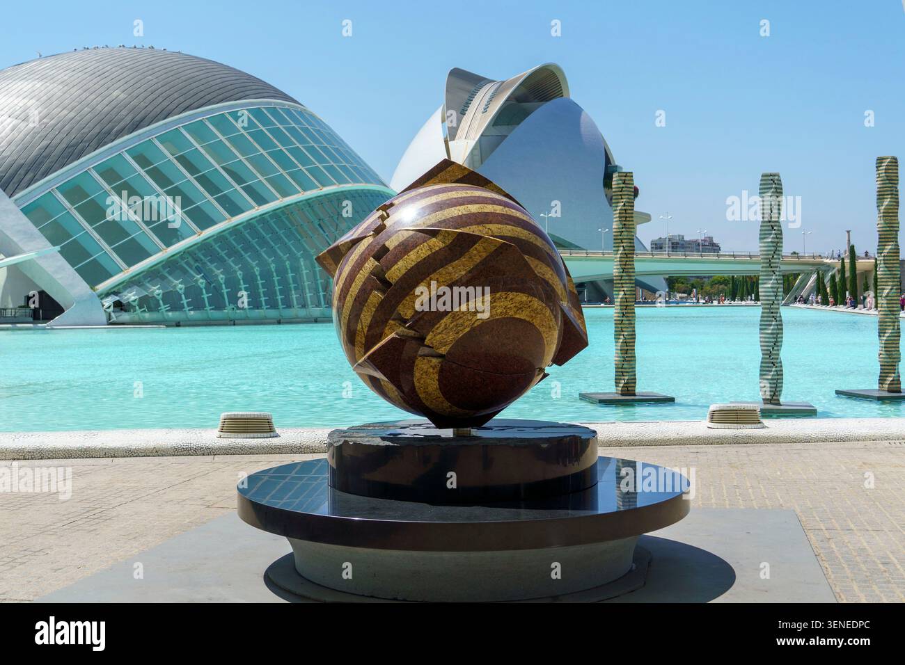 Une sculpture de sphère moderne avec les bâtiments futuristes emblématiques de la Cité des Arts et des Sciences de Valence Espagne sous un ciel bleu clair Banque D'Images