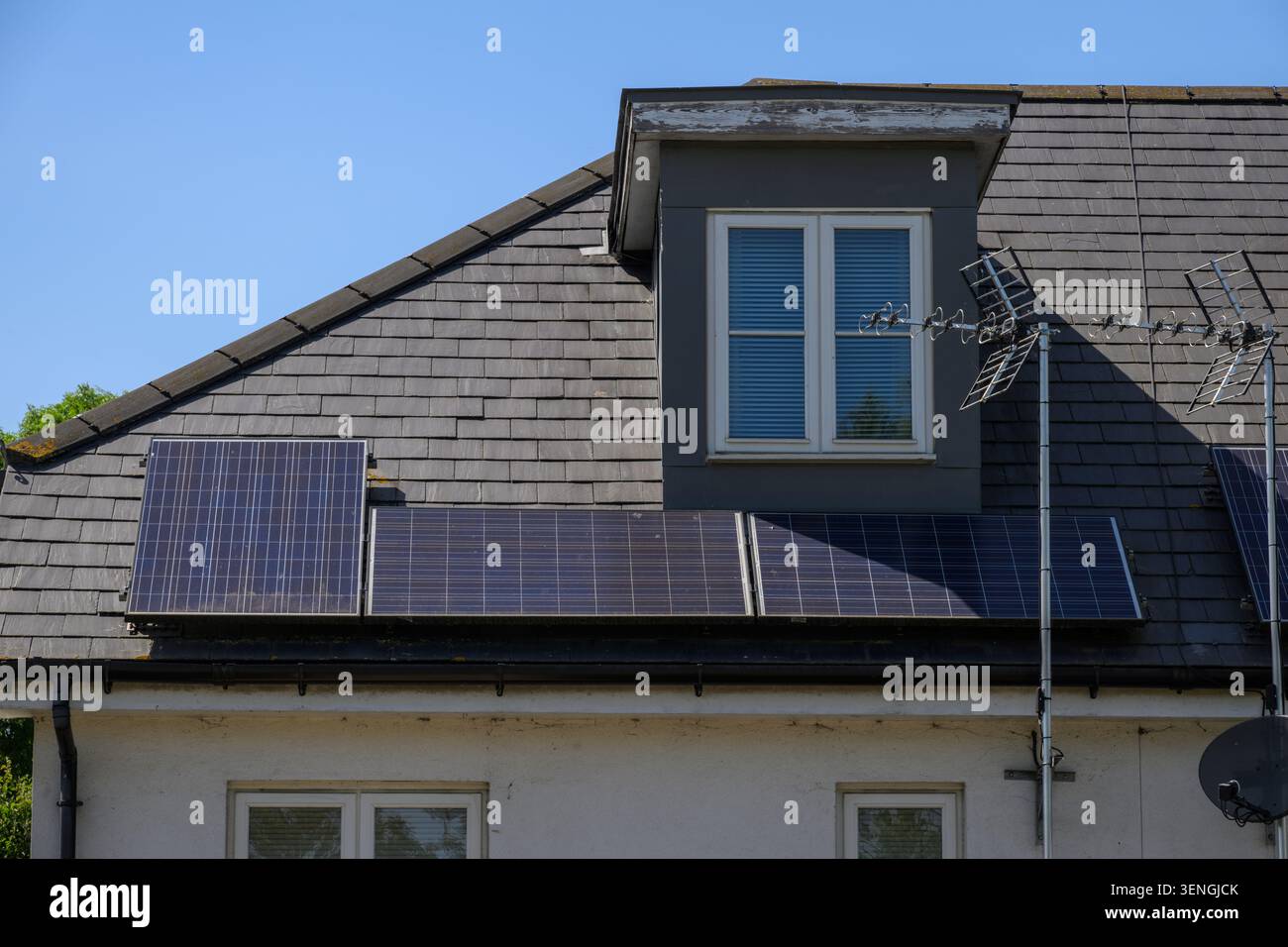 Toit de maison résidentielle équipé de panneaux solaires pour la production d'énergie renouvelable lors d'une journée ensoleillée brillante au Royaume-Uni. Banque D'Images