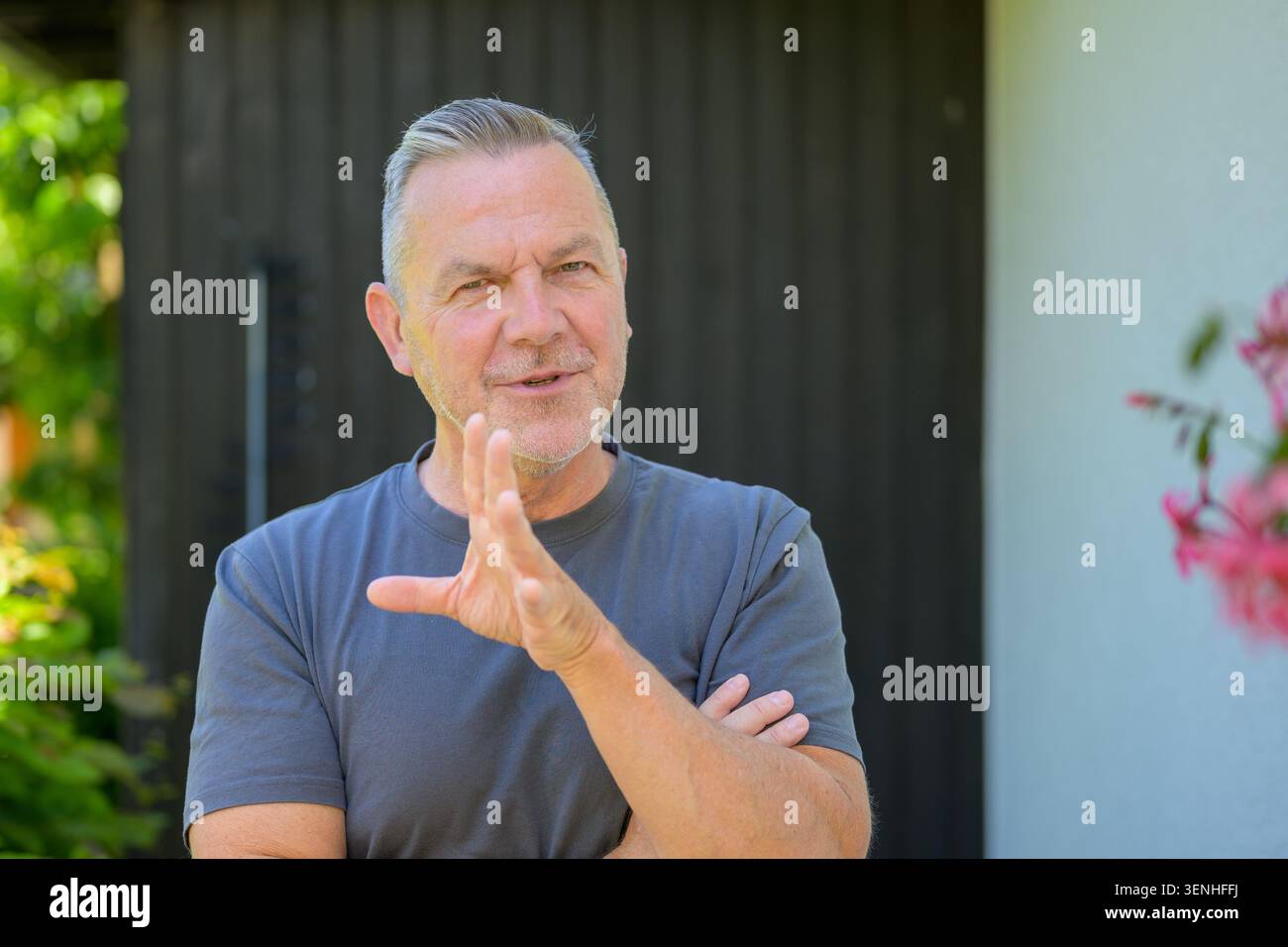 Homme mature confiant faisant des gestes tout en parlant à l'extérieur avec une expression calme et professionnelle. Portrait de style de vie authentique représentant la communicatio Banque D'Images