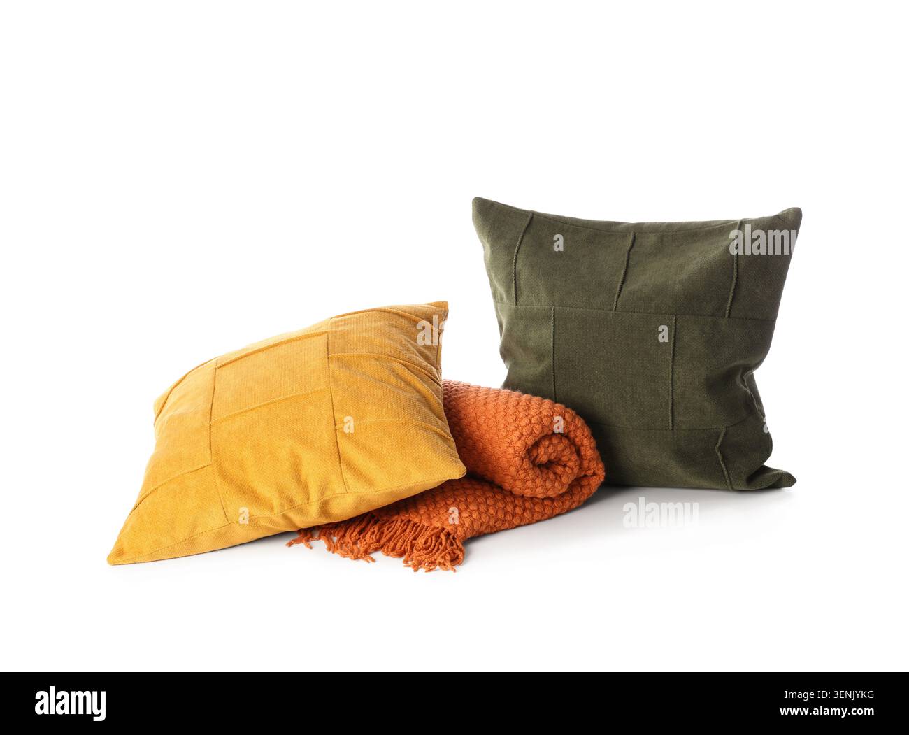 Arrangement de décoration de maison confortable avec des oreillers jaune moutarde et vert olive et une couverture tricotée orange roulée, les textiles présentent des textures distinctes et Banque D'Images