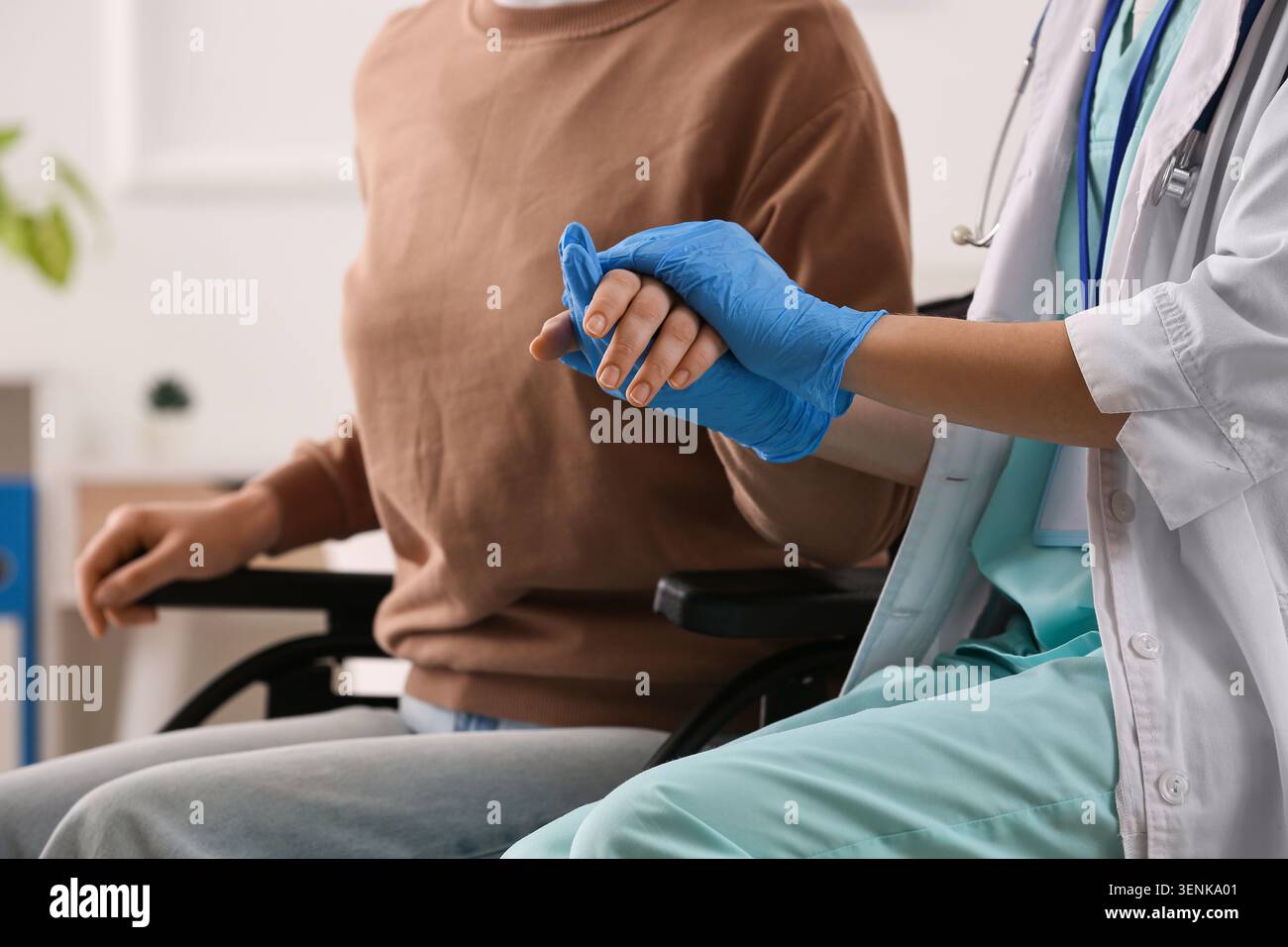 Professionnel de la santé portant des gants bleus tenant les patients par la main, fournissant un soutien et des soins compatissants dans le milieu de la santé Banque D'Images