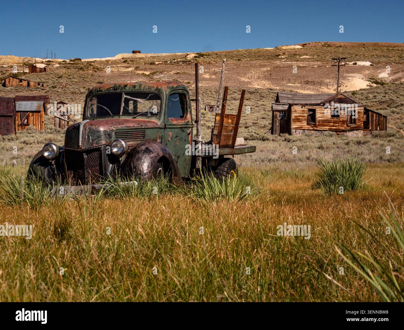 Voiture ancienne rouillée abandonnée dans les hautes herbes au parc historique de Bodie, ville fantôme, comté de Mono, Californie, États-Unis. Banque D'Images
