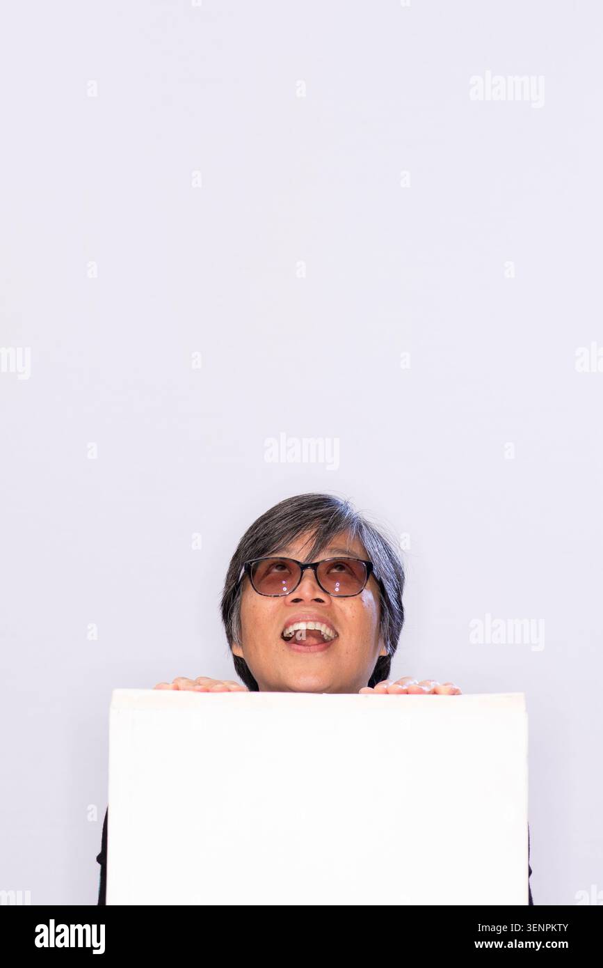 Candy Gourlay se tient avec un grand sourire, levant les yeux de derrière une surface blanche dans un studio. L'arrière-plan est léger et simple Banque D'Images