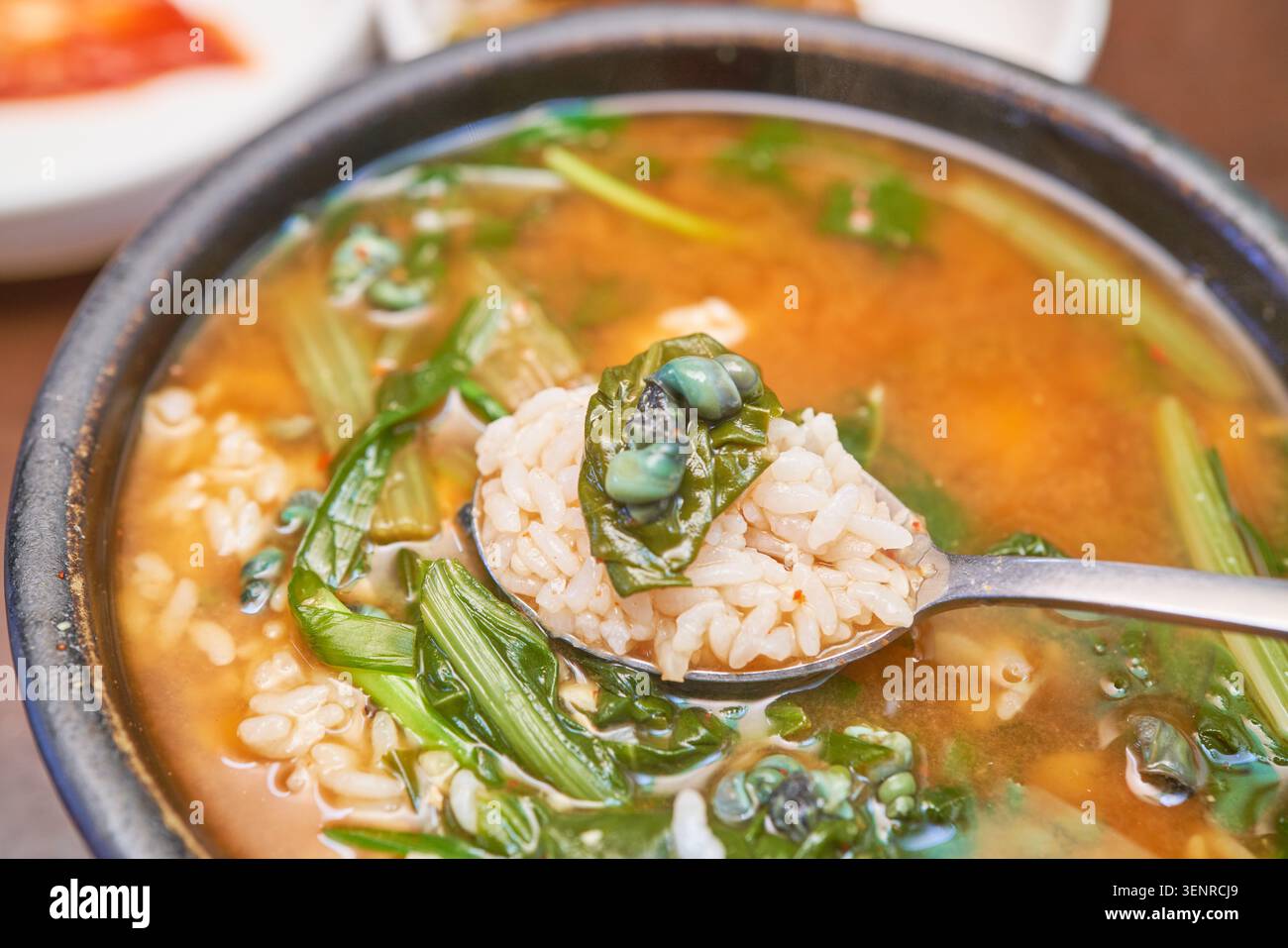 Une soupe traditionnelle à la gueule de bois composée d'escargots d'eau douce et de légumes verts servis avec du riz cuit à la vapeur et des accompagnements qui capturent la cuisine locale authentique Banque D'Images