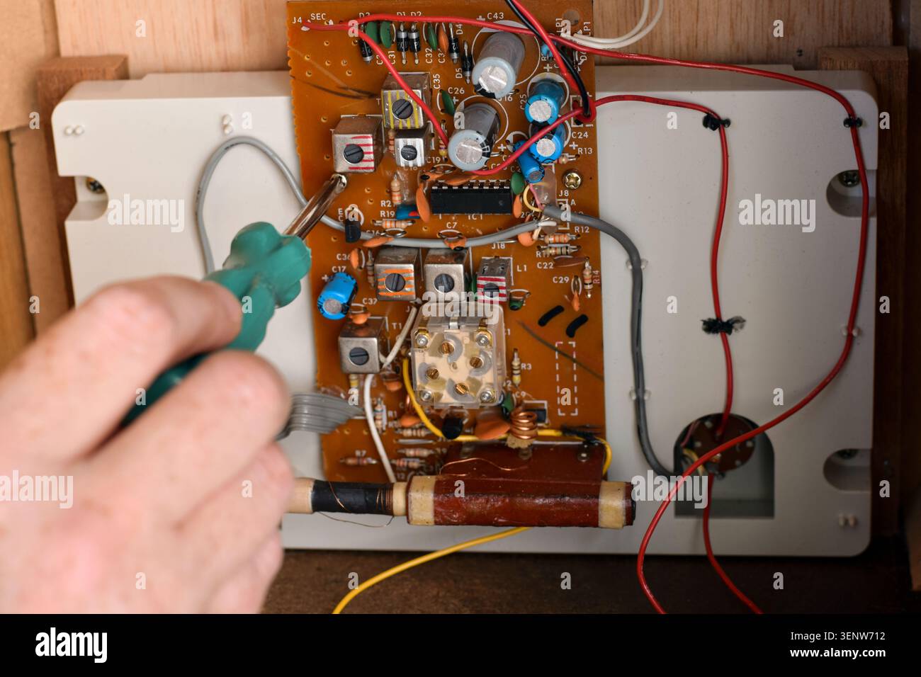 Fermez la main de la personne à l'aide d'un tournevis à l'intérieur de la radio vintage, mettant en évidence la réparation, la restauration, l'entretien et l'électronique rétro Banque D'Images