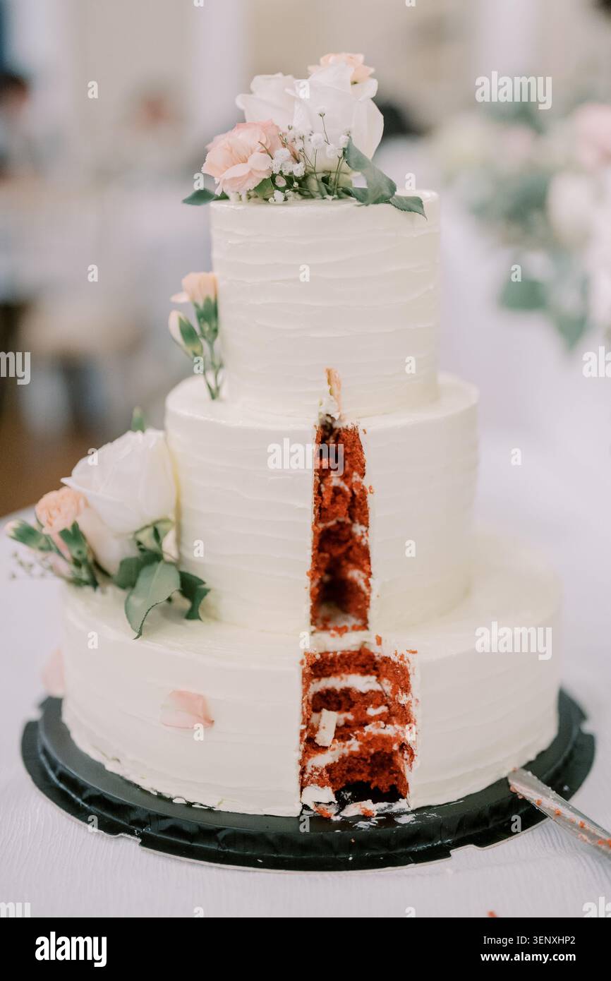 Gâteau de mariage à trois niveaux avec décorations florales et intérieur en velours rouge Banque D'Images