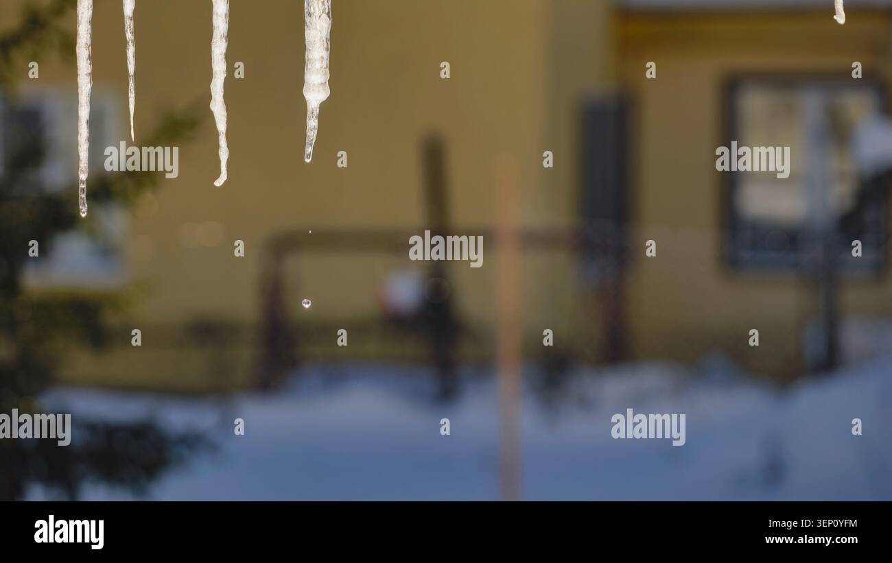 Glaçons fondant dans l'hiver dur en plein air, l'eau goutte à goutte du toit gelé de la maison Banque D'Images