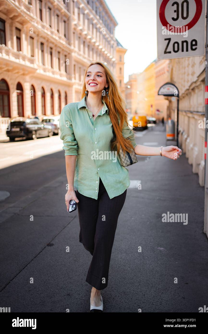 Jeune femme marchant et souriant dans une rue de Vienne Banque D'Images