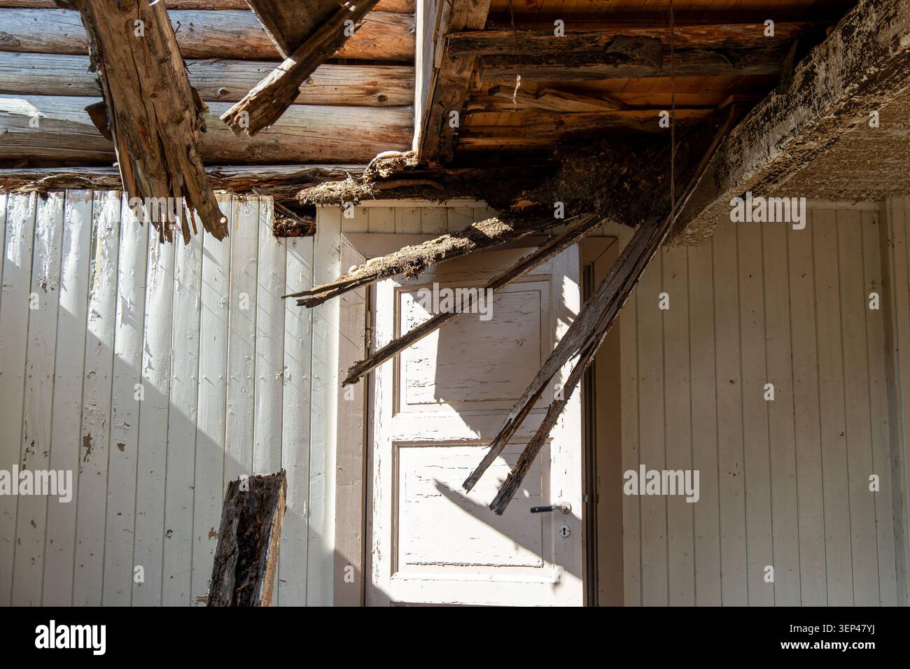 Lumière du soleil entrant dans une pièce qui s'effondre dans une maison en bois abandonnée avec des poutres de toit qui tombent, intérieur exposé et grave décomposition structurelle Banque D'Images