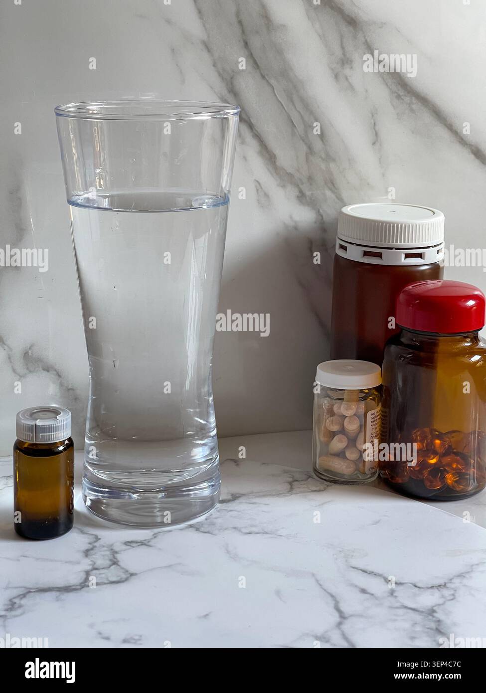 Suppléments vitaminiques avec un verre d'eau représentant un mode de vie sain et une routine de bien-être quotidienne. - Image de stock capturée avec un smartphone