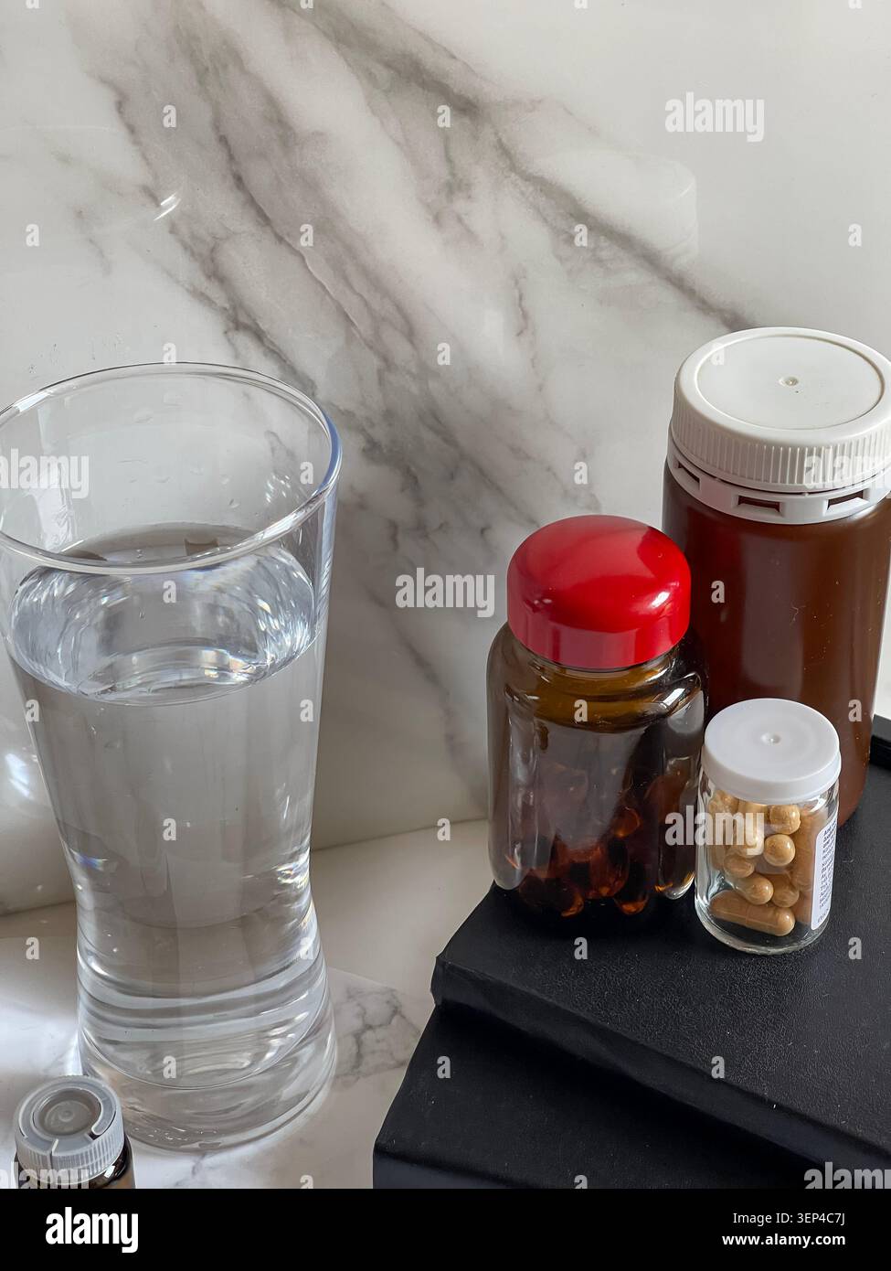 Suppléments vitaminiques avec un verre d'eau représentant un mode de vie sain et une routine de bien-être quotidienne. - Image de stock capturée avec un smartphone