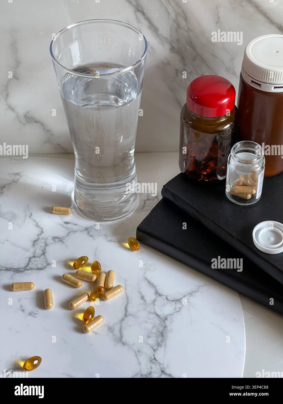Suppléments vitaminiques avec un verre d'eau représentant un mode de vie sain et une routine de bien-être quotidienne. - Image de stock capturée avec un smartphone