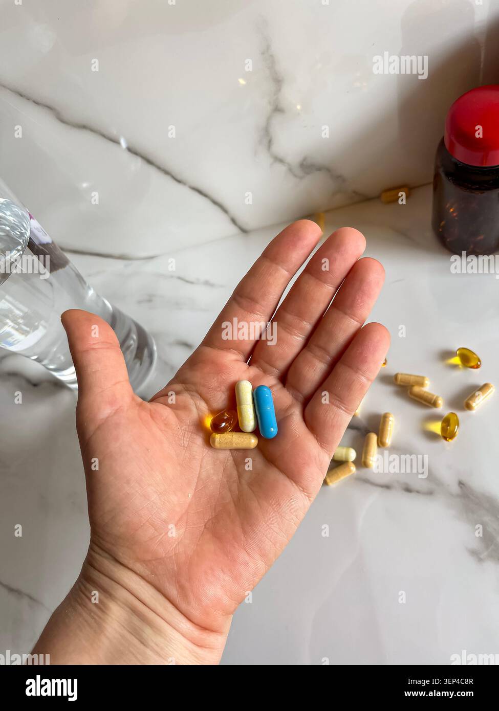 Main tenant des capsules de vitamines colorées pour un mode de vie sain et une supplémentation. - Image de stock capturée avec un smartphone