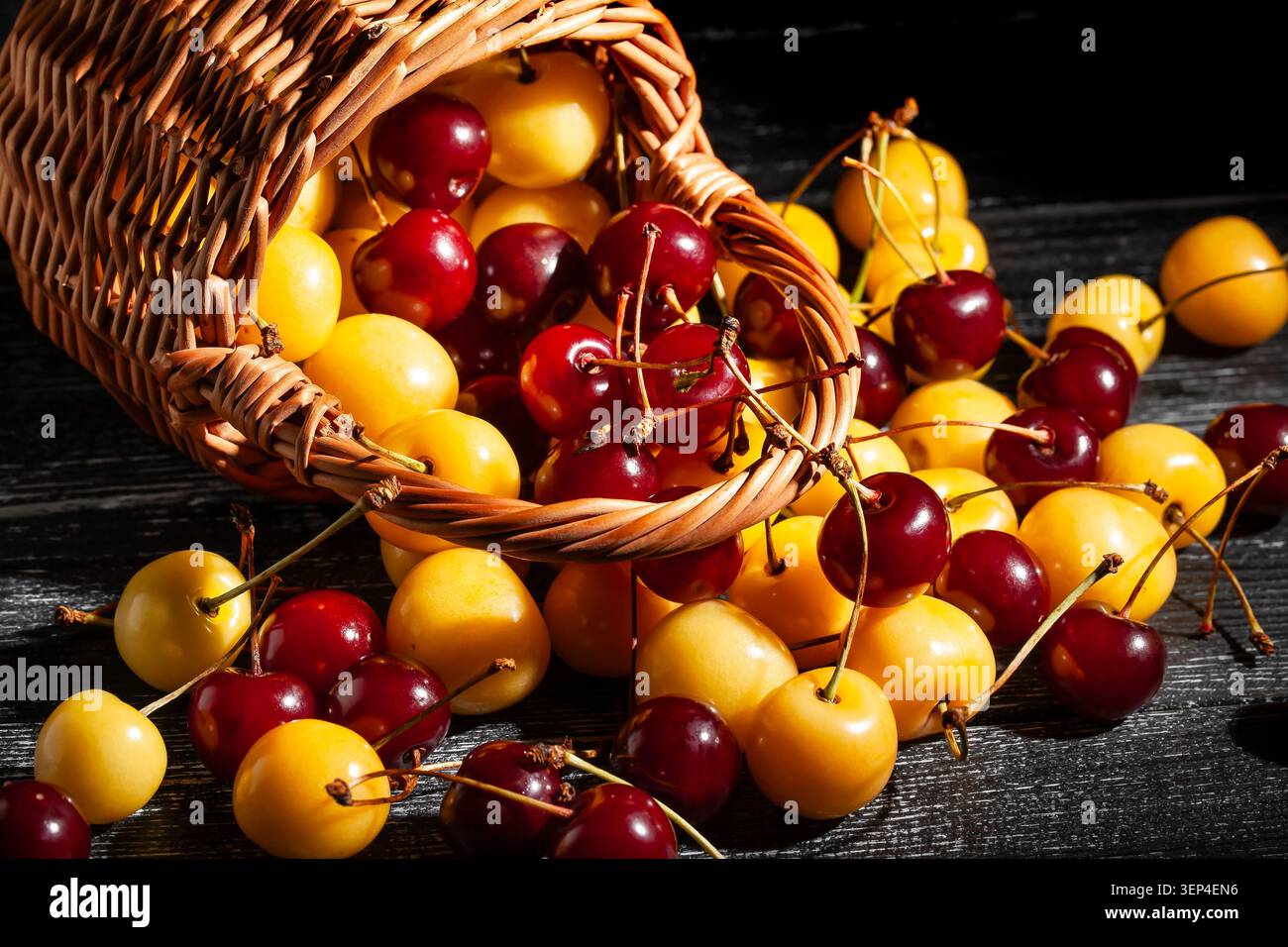 panier de mélange de cerise jaune rouge sur fond de bois noir Banque D'Images