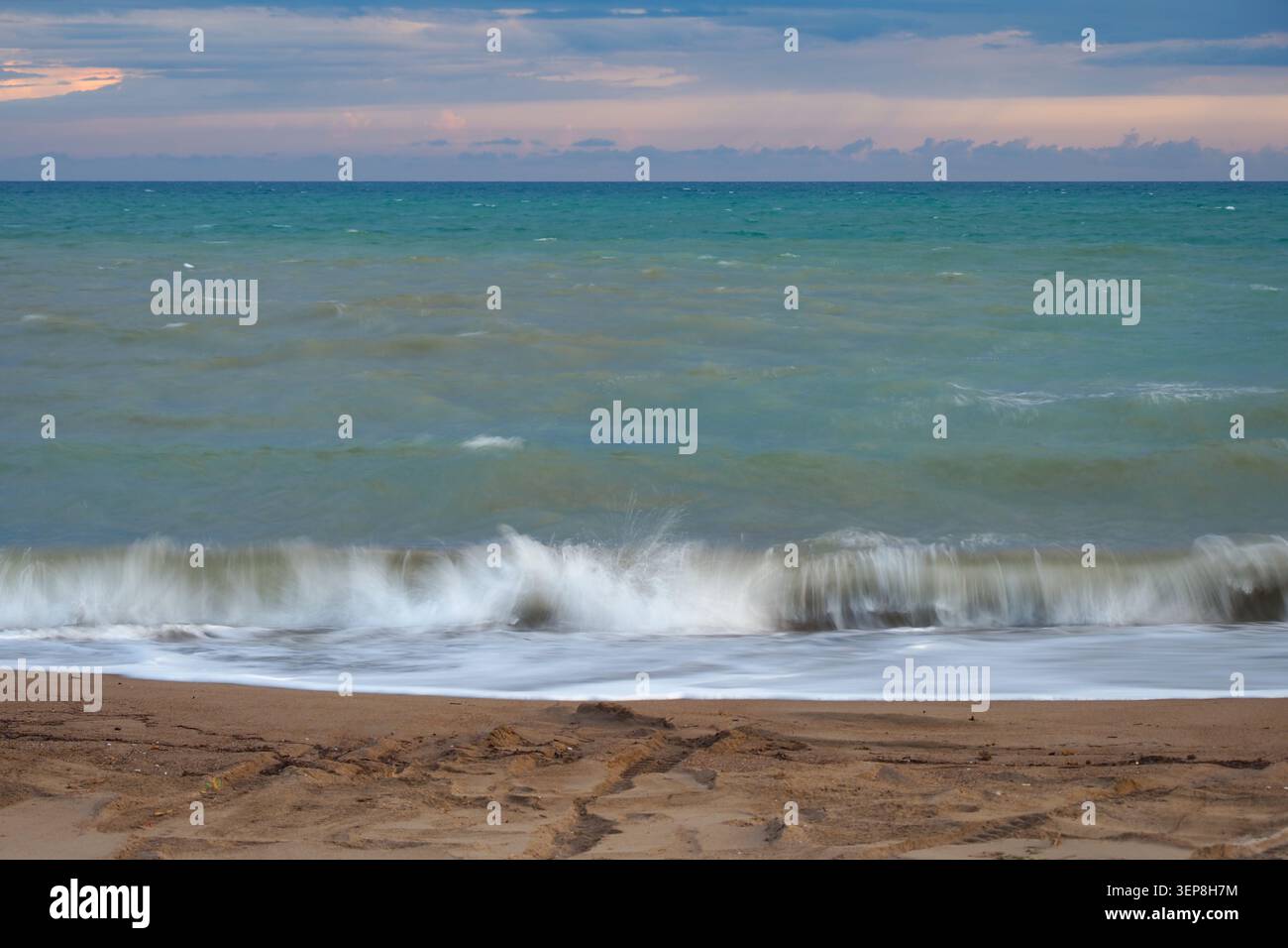 Vagues se brisant sur la plage de sable fin d'après-midi Banque D'Images