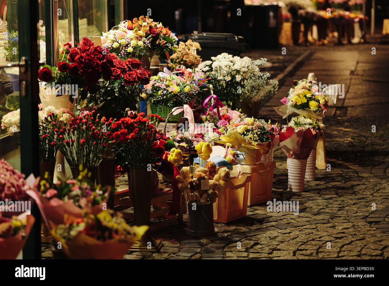 Bouquets de fleurs affichés à l'étal de marché extérieur la nuit. Shopping floral et concept d'entreprise de fleurs fraîches. Banque D'Images
