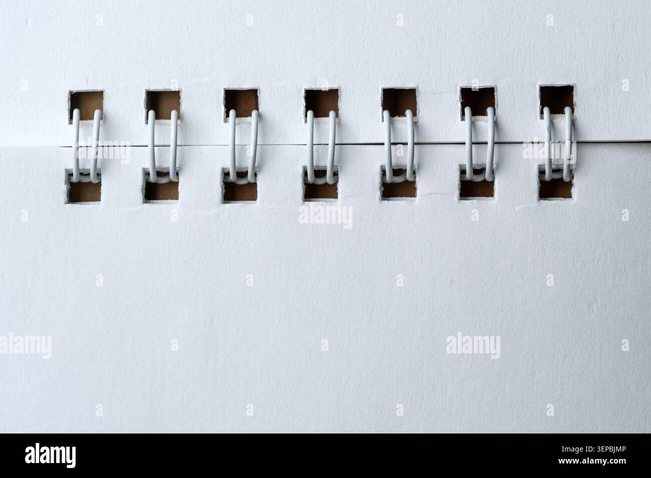 Les pinces à reliure blanches maintiennent ensemble les feuilles de papier empilées en toute harmonie. Banque D'Images