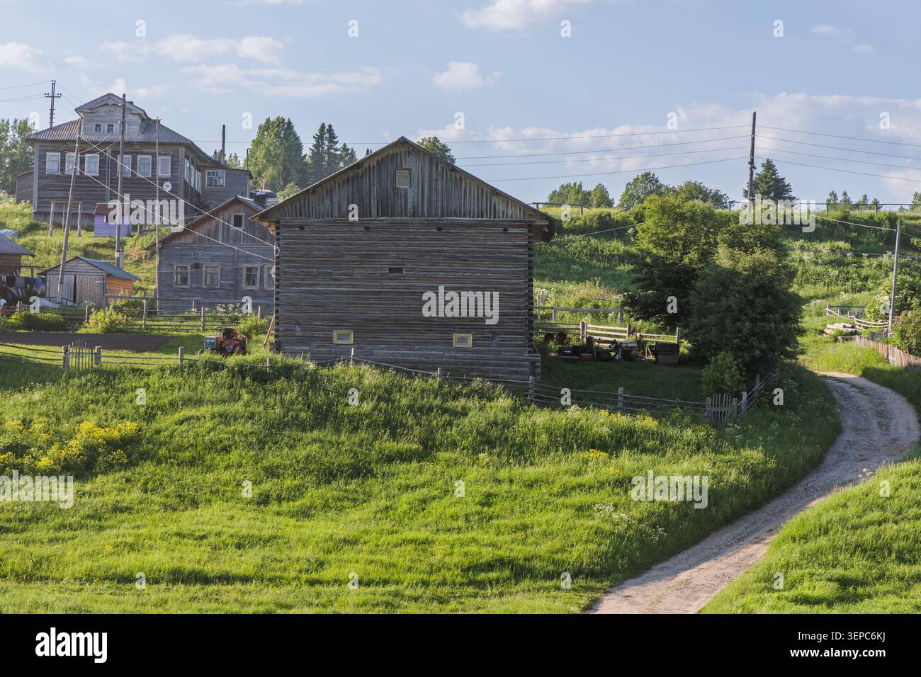 Un village sur une colline au-dessus d'une vallée verdoyante. Une route étroite mène au village. Style russe. Banque D'Images