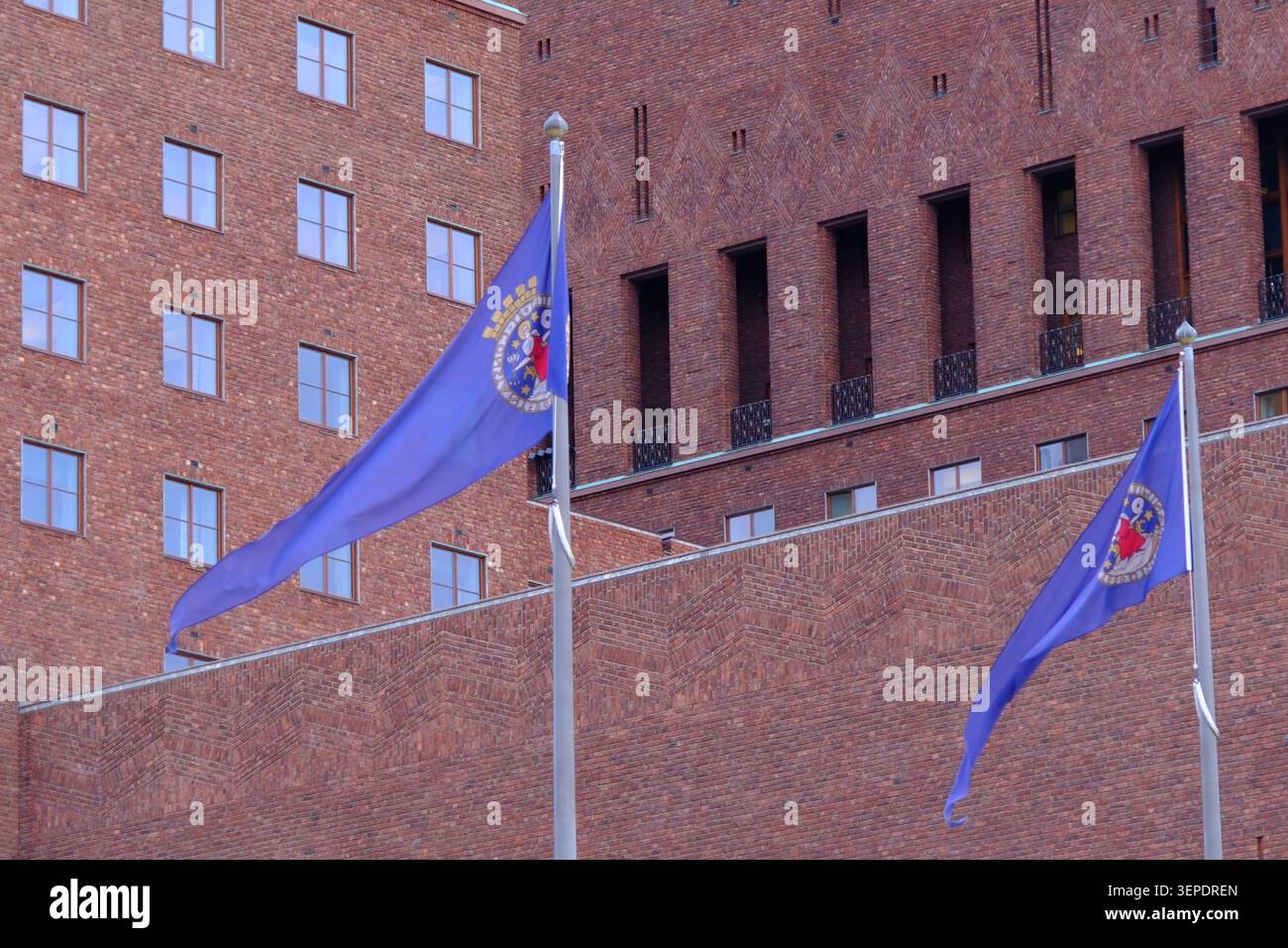 Oslo, Norvège-26 novembre 2025 : drapeaux d'Oslo volant dans le vent devant le bâtiment en briques rouges de l'hôtel de ville d'Oslo. Banque D'Images