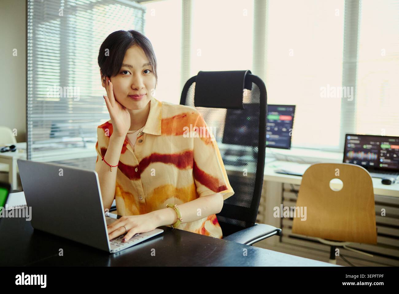 Portrait de jeune femme asiatique assistant d'affaires ou secrétaire travaillant sur ordinateur portable dans le bureau, souriant et regardant la caméra. Idéal pour la productivité sur le lieu de travail, le démarrage, la communication d'entreprise Banque D'Images