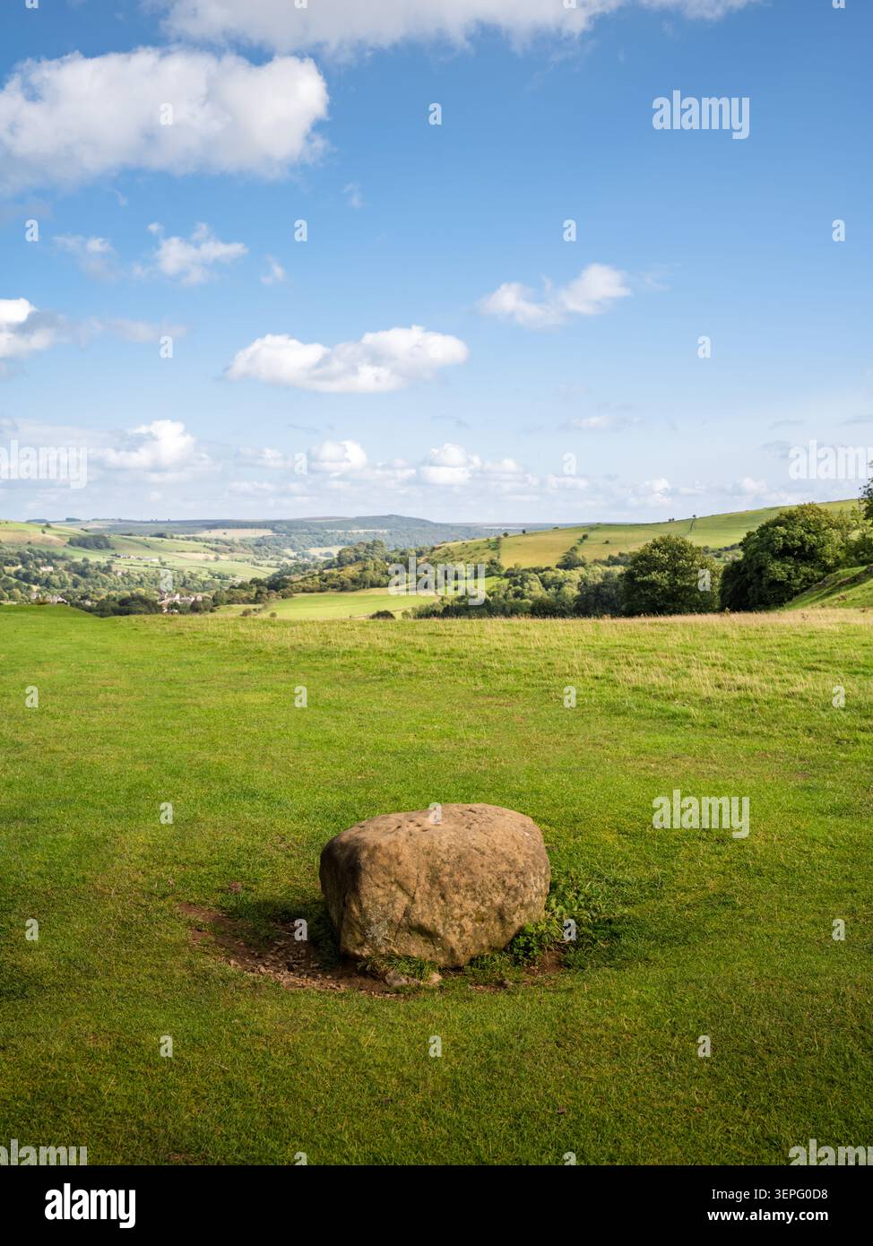 Vue verticale portrait de la pierre frontière historique d'Eyam assis dans un pâturage vert ouvert surplombant les collines ondulantes du Peak District Banque D'Images
