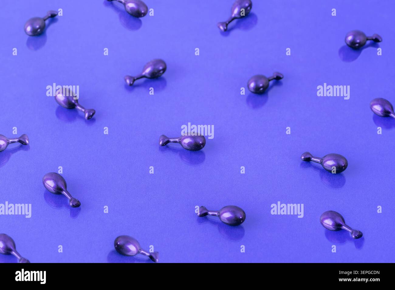 Capsules de sérum cosmétique violet sur fond violet brillant, modèle de soins de la peau de beauté avec texture réfléchissante, concept de bien-être. Banque D'Images