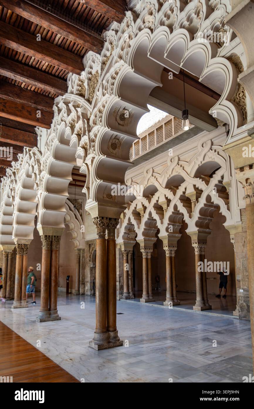 Saragosse, Espagne - 17 août 2022 : les visiteurs admirent les arches islamiques ornées et le stuc sculpté à l'intérieur du palais historique de l'Aljaferia. Banque D'Images