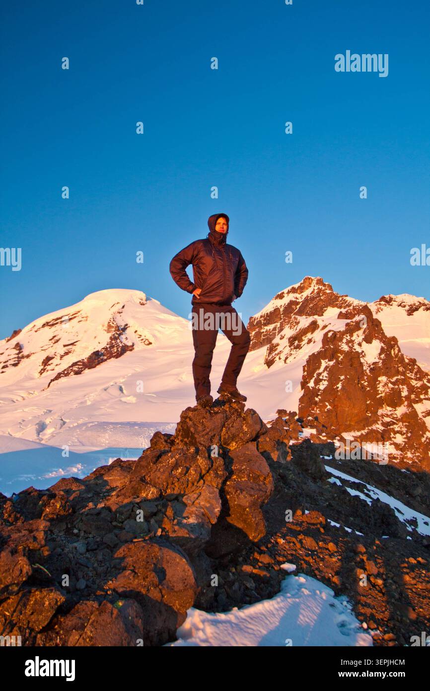 Randonneur se tient sur la crête rocheuse avec un volcan couvert de neige derrière. Banque D'Images
