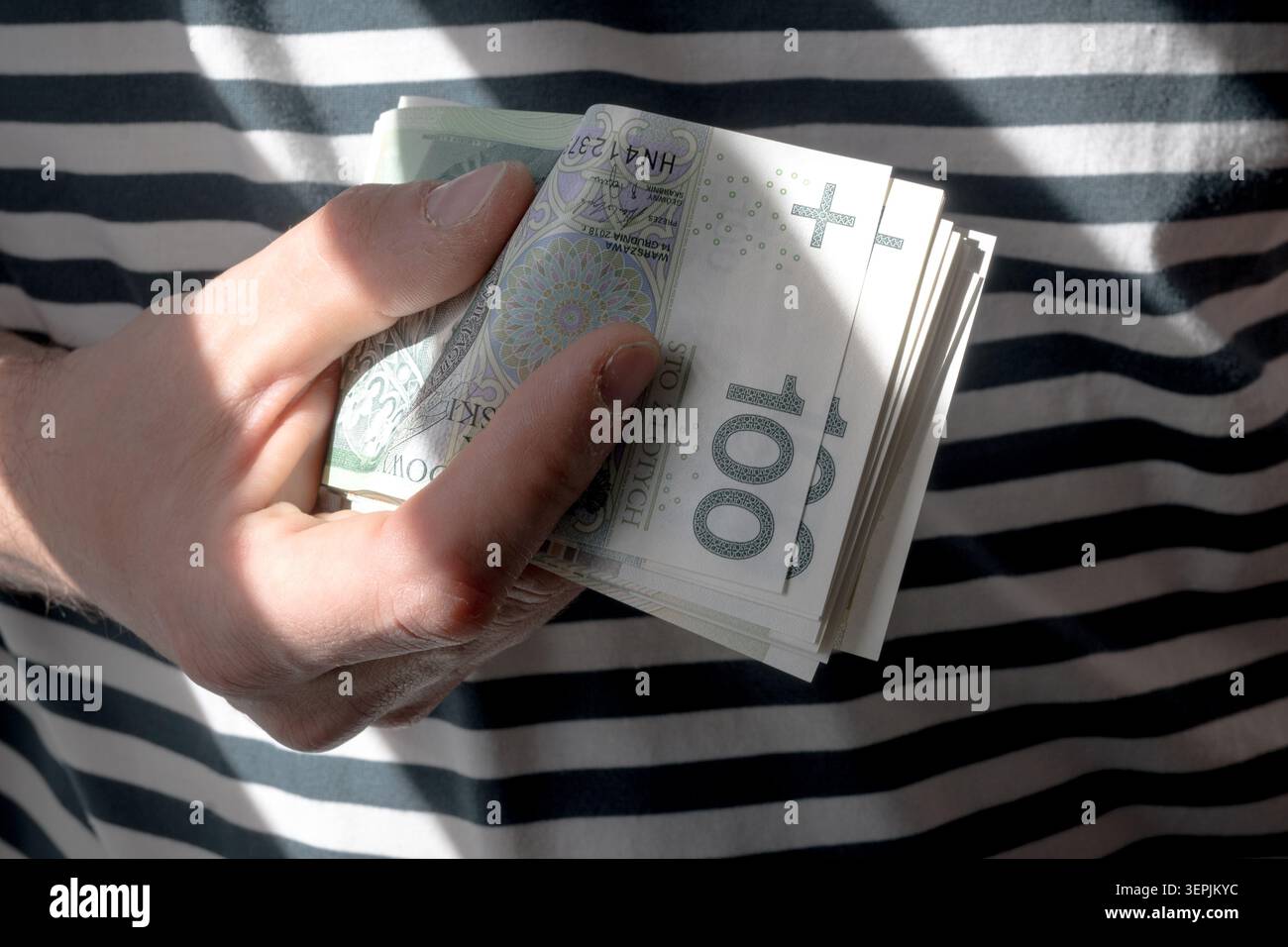 L'homme tient des billets de banque polonais de cent zloty dans sa main. Banque D'Images