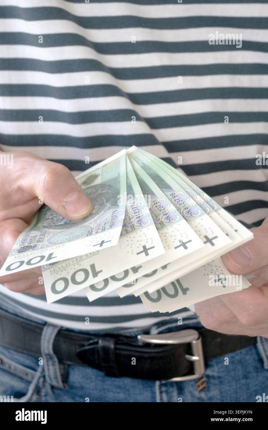 L'homme tient des billets de banque polonais de cent zloty dans sa main. Banque D'Images