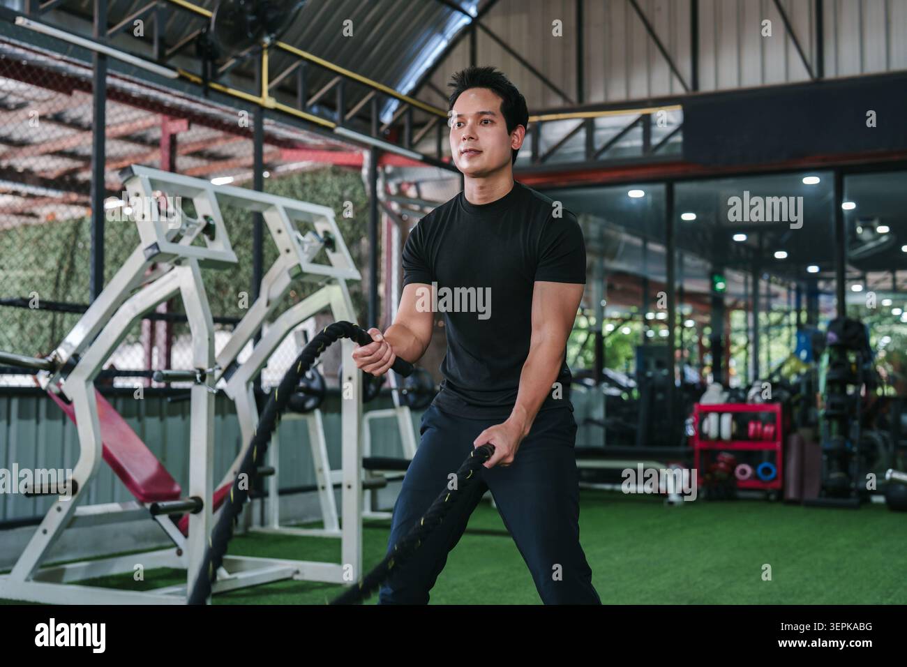 Homme asiatique faisant une séance d'entraînement de fitness avec des cordes de combat pour la musculation et un mode de vie sain actif Banque D'Images