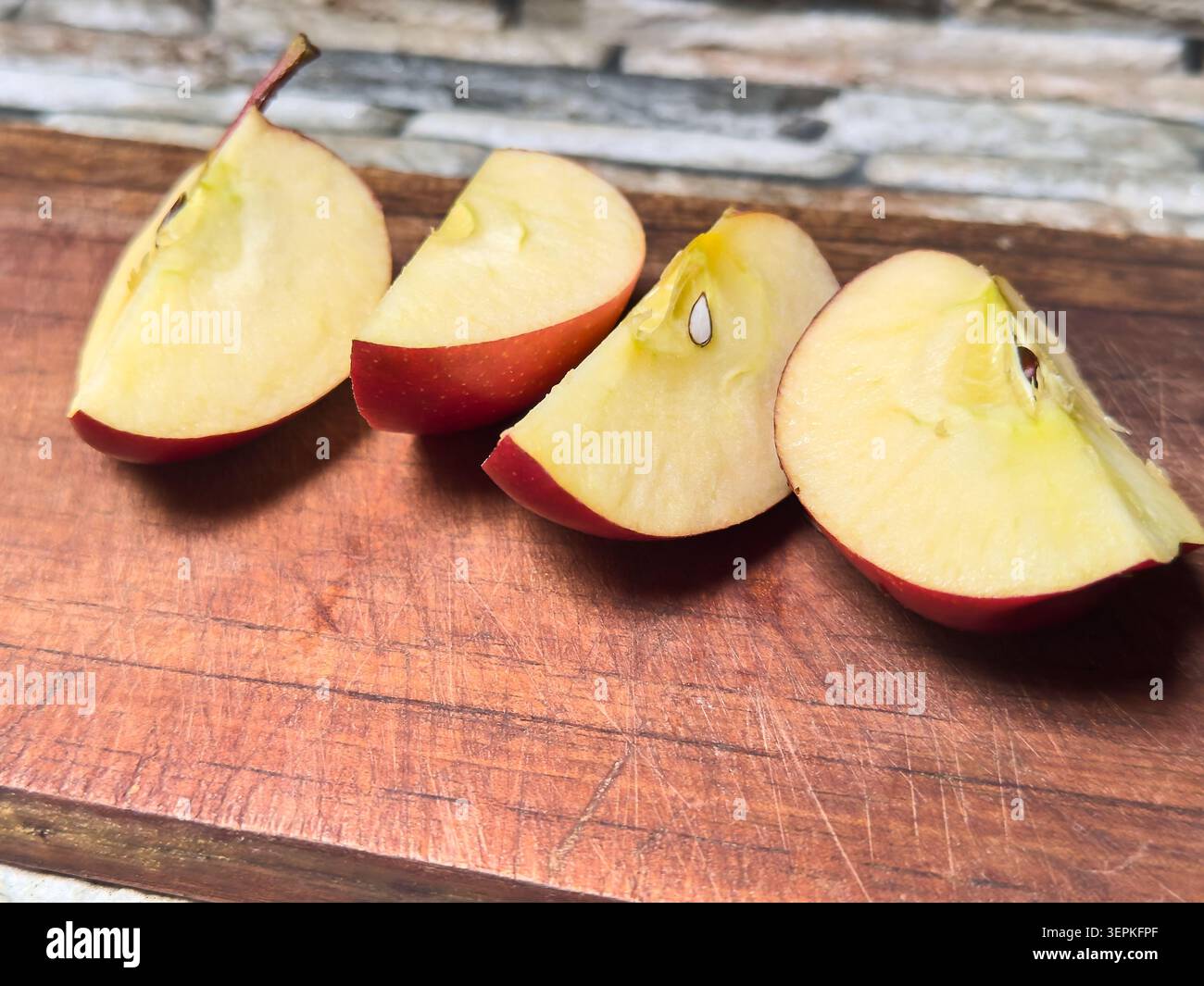 quartiers de pommes rouges tranchés sur planche à découper en bois rayé, morceaux de fruits juteux frais mûrs avec chair et graines, concept de régime sain avec espace de copie Banque D'Images