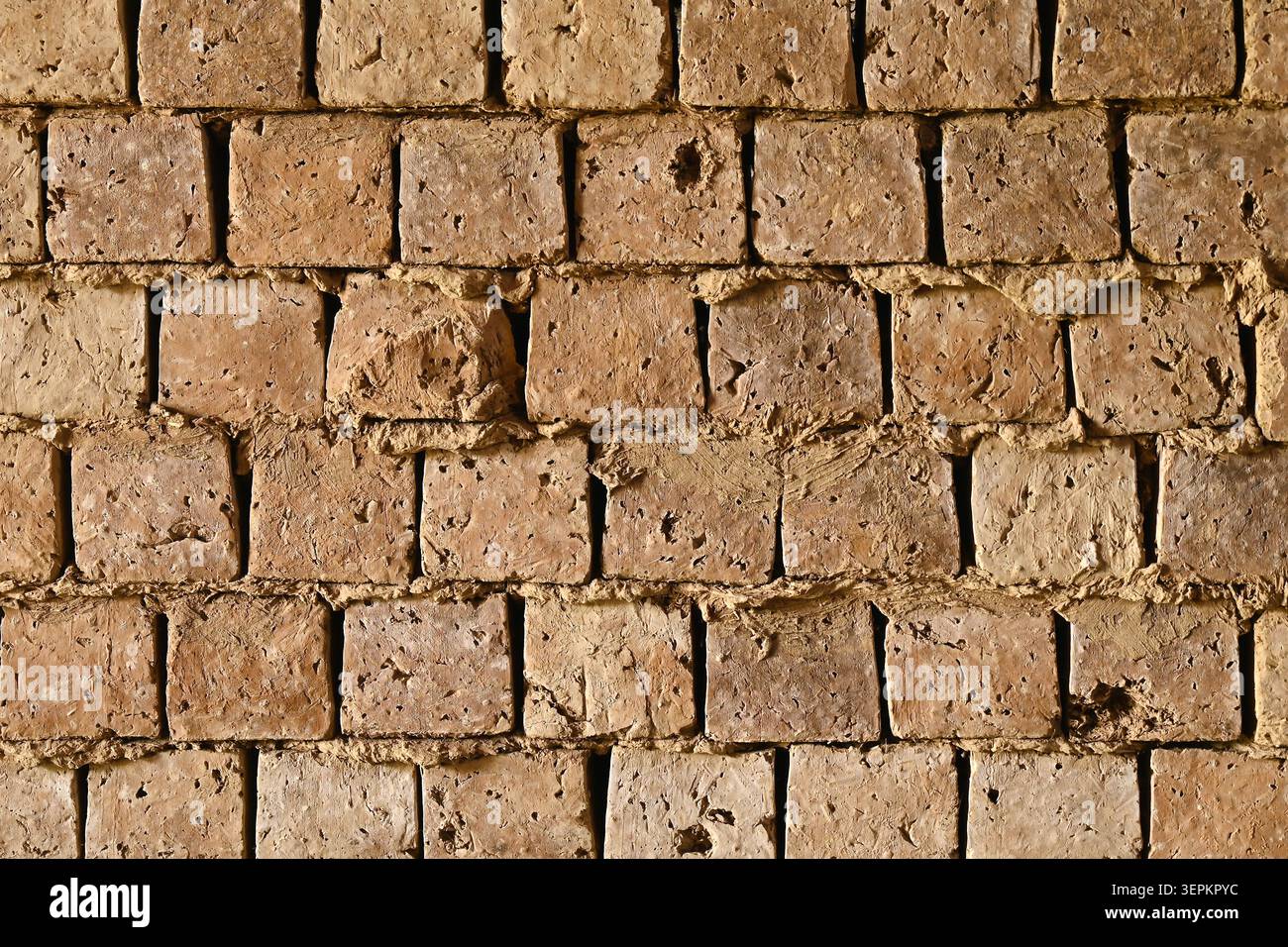 Fond de texture de mur de briques de boue altérée faite de briques adobe faites à la main pour la construction rustique Banque D'Images