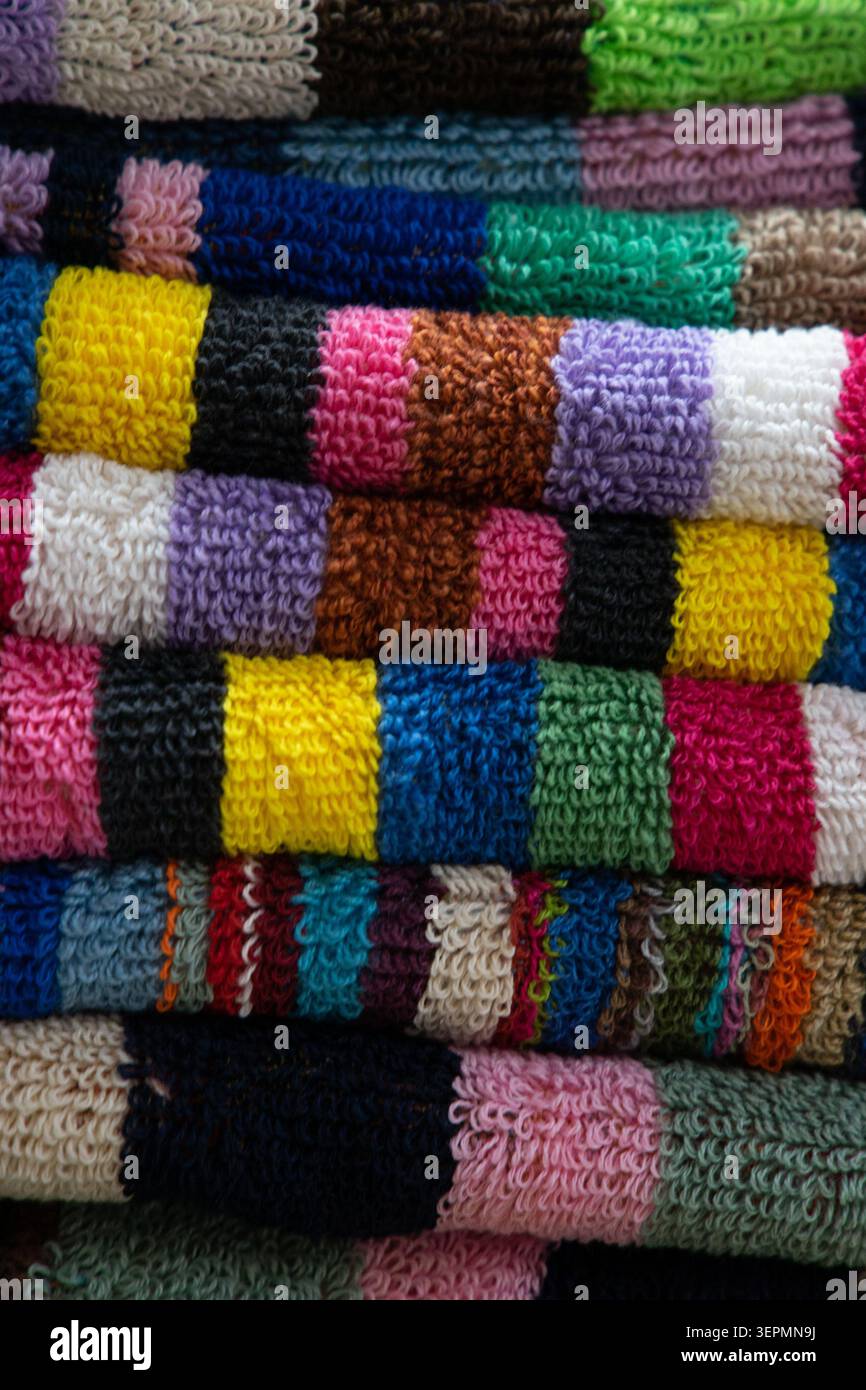 Plan macro mettant en évidence la texture du tissu éponge moelleux et les bandes de couleurs vives de serviettes de bain ou de plage empilées Banque D'Images