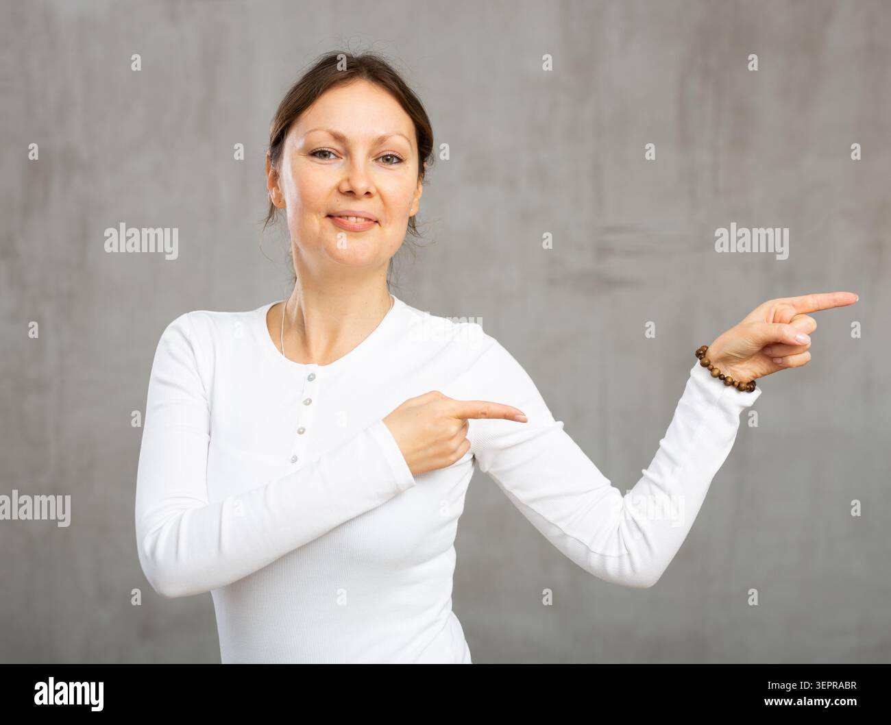 Femme gaie avec le sourire large sur son visage exsurant le bonheur et la positivité pointant Banque D'Images