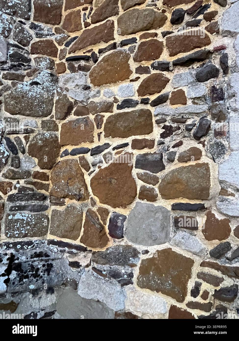 Mur de carrstone altéré à Downham Market, Norfolk, montrant des pierres naturelles irrégulières, du mortier léger et un style de construction de ville en pain d'épices distinctif. - Image de stock capturée avec un smartphone
