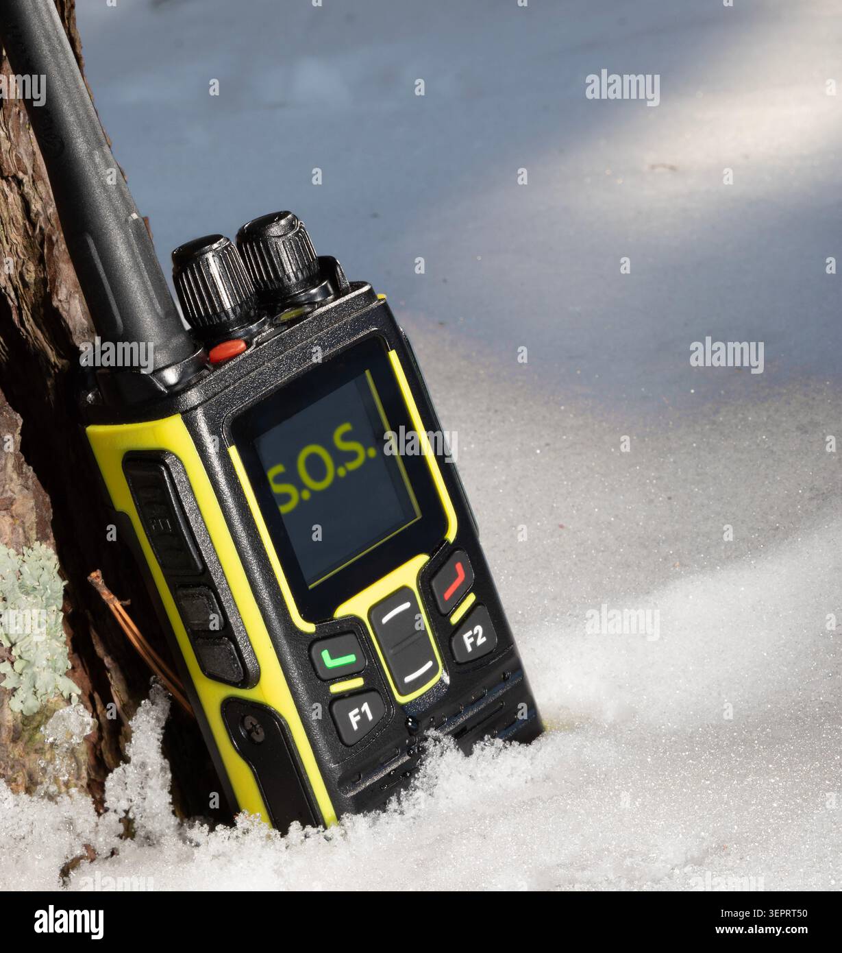 Quelqu'un en détresse envoyant un signal SOS qui a été capté par un talkie-walkie noir et jaune dans la neige après une tempête hivernale. Banque D'Images