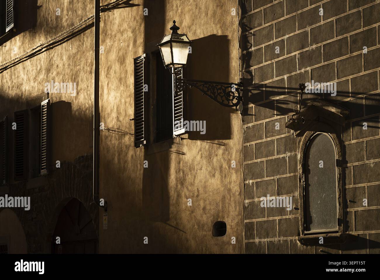 Un mur de maison illuminé par le soleil du soir avec des fenêtres et un lampadaire qui projette des ombres, vieille ville, Florence, Toscane, Italie Banque D'Images