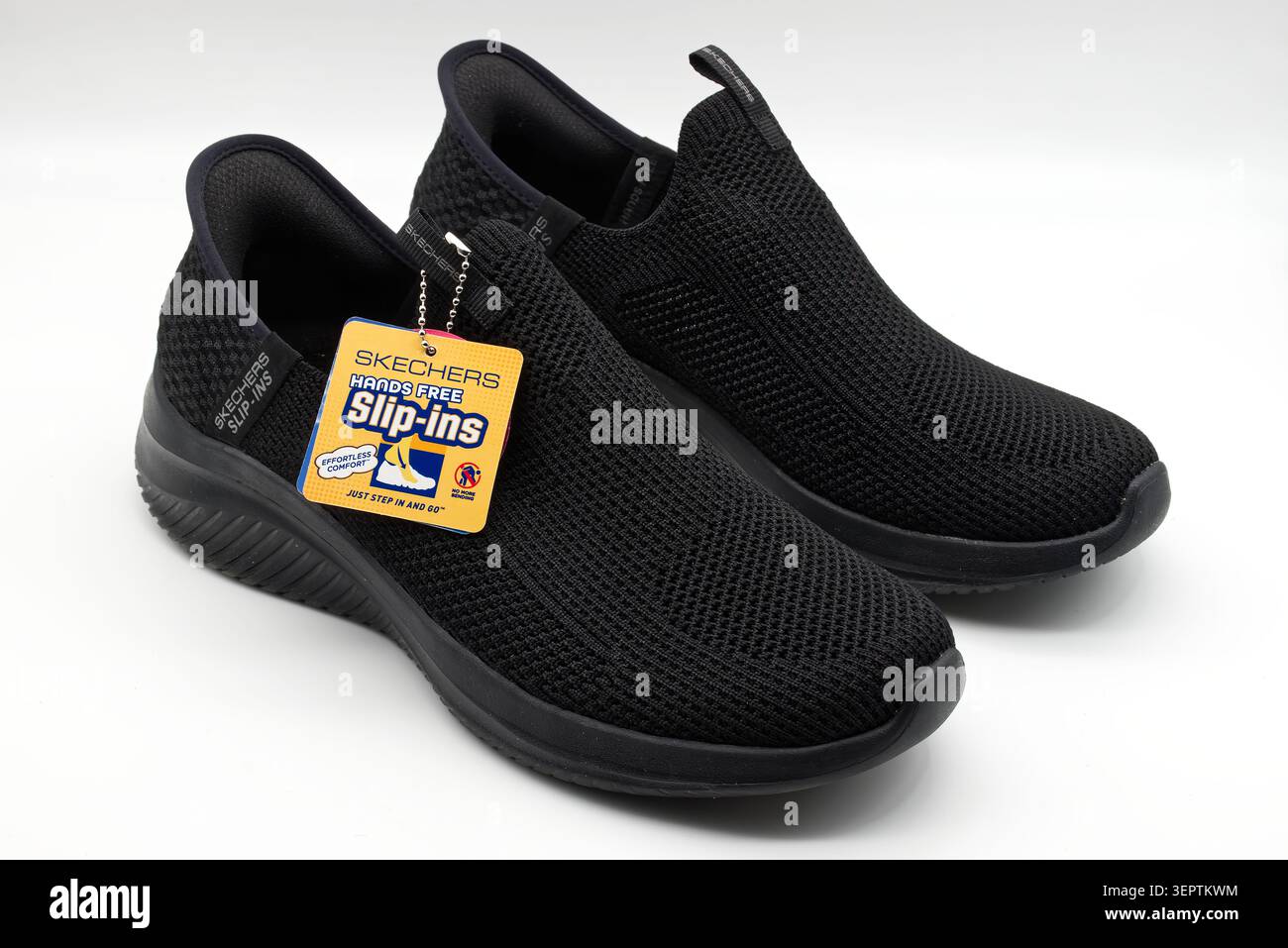 Paire de skechers noirs mains libres glissantes chaussures de marche confortables avec étiquette de détail sur fond blanc. Banque D'Images