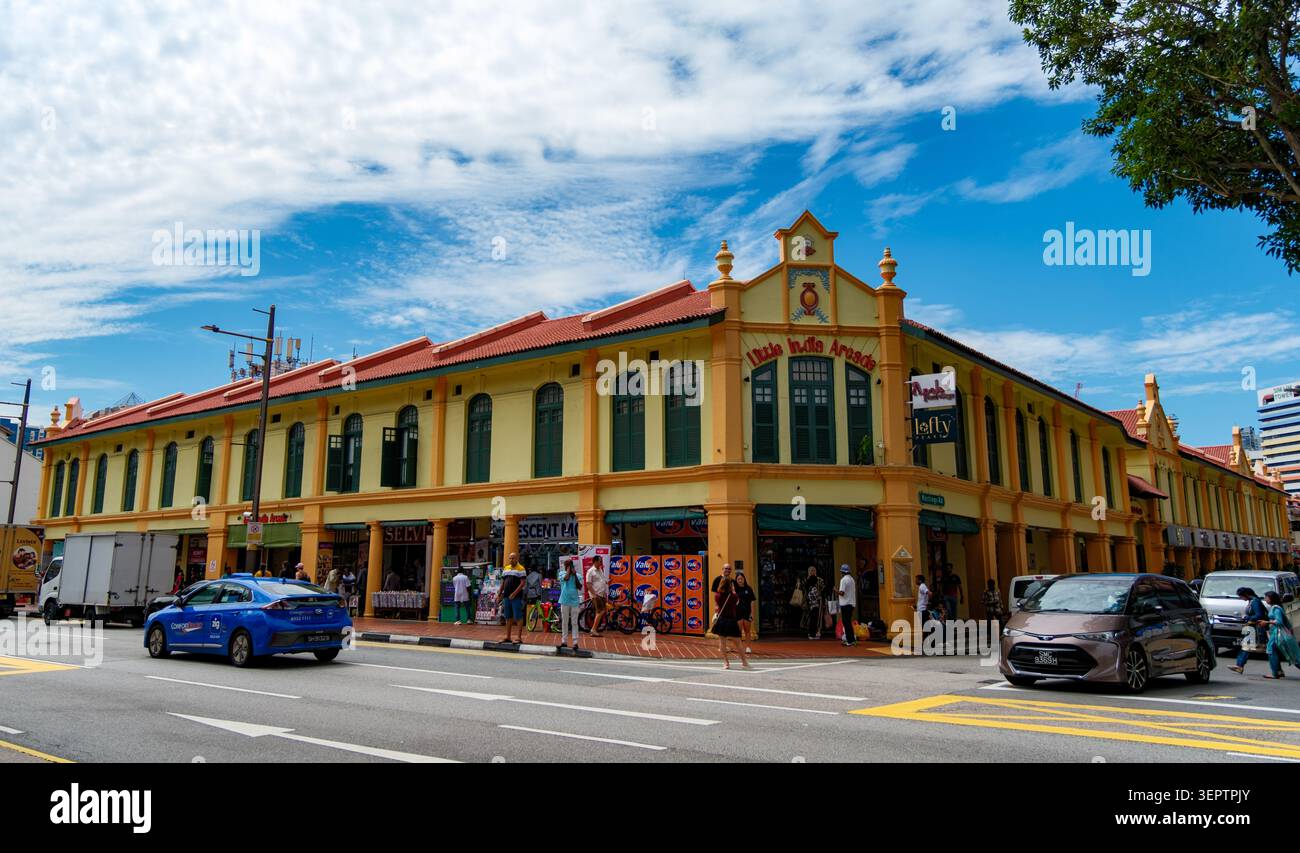 Boutiques historiques colorées dans le quartier patrimonial Kampong Glam de Singapour sous un ciel bleu vif avec circulation routière et voitures qui passent. Banque D'Images