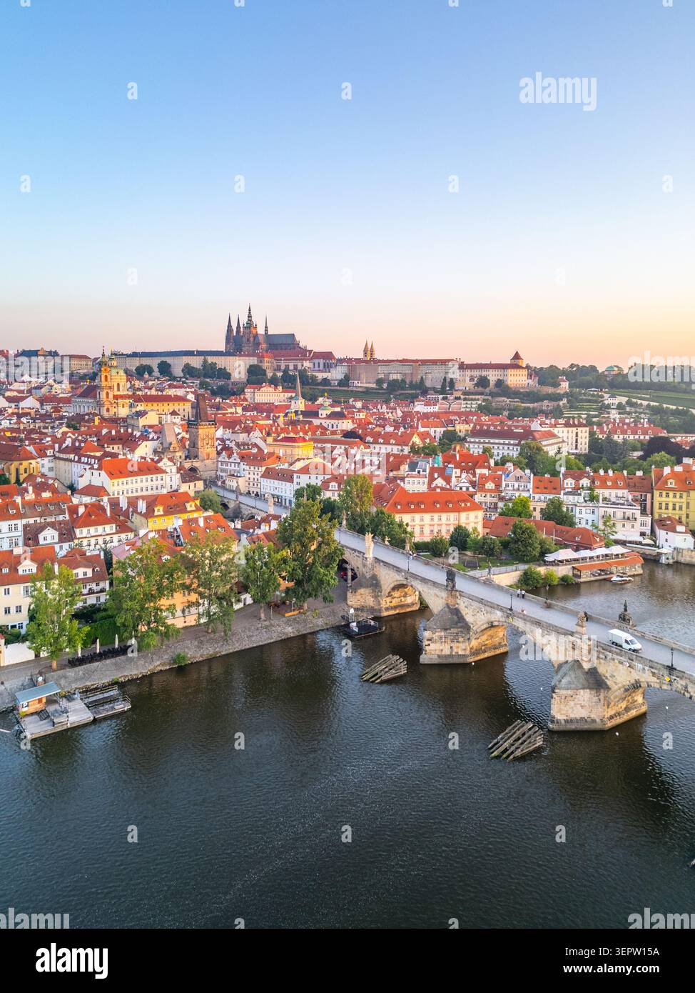 La lumière du matin jette une lumière chaude sur le paysage historique de Prague, mettant en évidence la rivière Vltava et le pont Charles. Banque D'Images